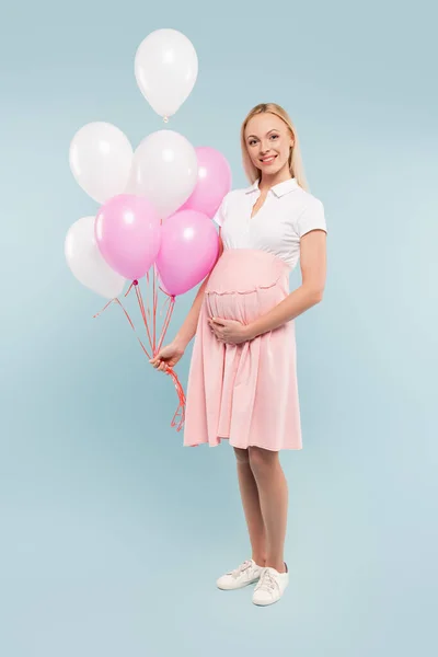 Volle Länge der schwangeren Frau mit Luftballons auf blau — Stockfoto