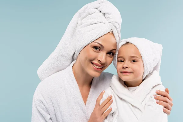 Mãe alegre e criança em roupões de banho sorrindo isolado em azul — Fotografia de Stock