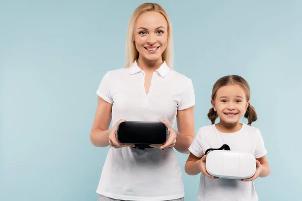 Cheerful mother and kid holding vr headsets isolated on blue — Stock Photo