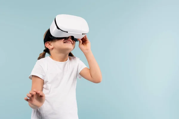 Criança alegre ajustando vr fone de ouvido isolado em azul — Fotografia de Stock