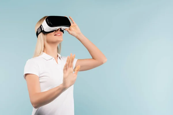 Mulher feliz em vr fone de ouvido gesticulando isolado em azul — Fotografia de Stock