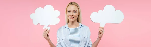 Heureuse femme blonde tenant des bulles de pensée isolées sur rose, bannière — Photo de stock