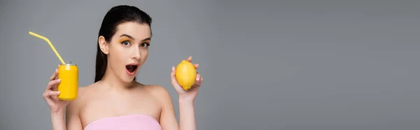 Jovem mulher espantada segurando lata amarela com refrigerante e limão isolado em cinza, banner — Fotografia de Stock