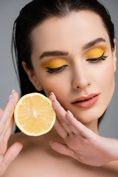 Jeune femme aux épaules nues tenant la moitié du citron juteux isolé sur gris — Photo de stock