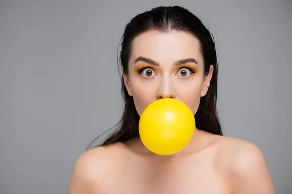 Femme brune avec maquillage soufflant jaune bubblegum isolé sur gris — Photo de stock