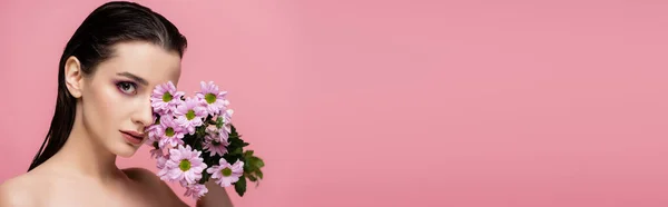Молодая чувственная женщина держит цветы изолированы на розовый, баннер — стоковое фото