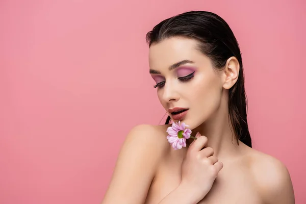 Sensual jovem segurando flor e olhando para longe isolado em rosa — Fotografia de Stock