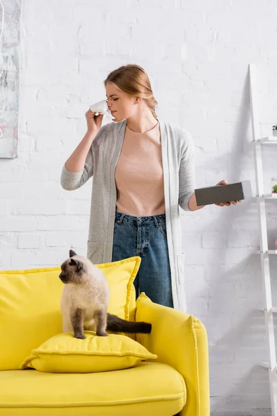 Young woman suffering from snuffle near siamese cat — Stock Photo