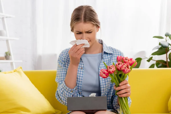 Woman with allergy on pollen holding napkin and tulips — Stock Photo