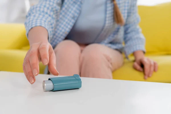 Cropped view of woman taking inhaler during allergy on blurred background — Stock Photo