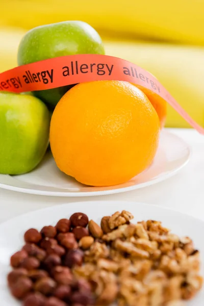 Ruban avec inscription allergique près des fruits frais et des noix au premier plan flou — Photo de stock
