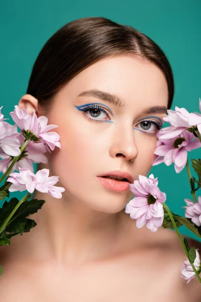 Portrait of charming woman near pink chrysanthemums isolated on green — Stock Photo