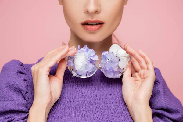 Vue partielle de la femme en chemisier violet tenant des lunettes avec des fleurs isolées sur rose — Photo de stock