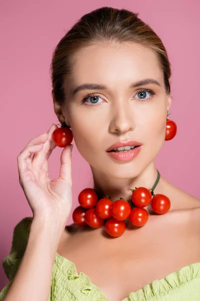 Femme sensuelle en collier et boucles d'oreilles en tomates cerise rouge sur rose — Photo de stock