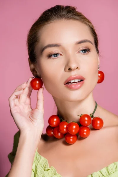 Mujer sensual en collar y pendientes hechos de tomates cherry rojos frescos en rosa - foto de stock