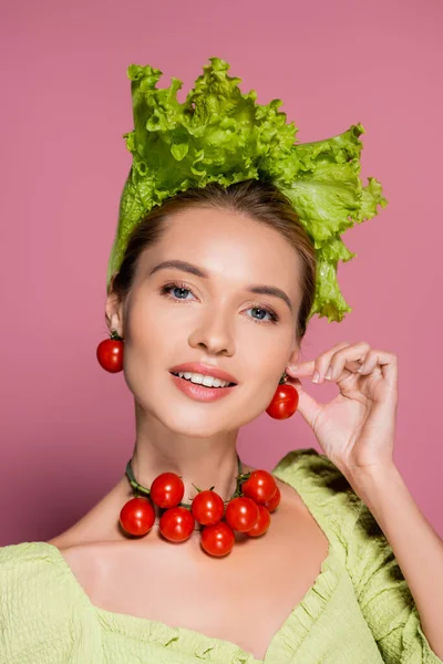 Femme souriante en chapeau, collier et boucles d'oreilles en légumes frais posant sur rose — Photo de stock