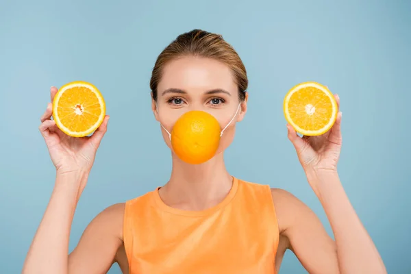 Young woman in protection mask made of orange looking at camera isolated on blue — Stock Photo