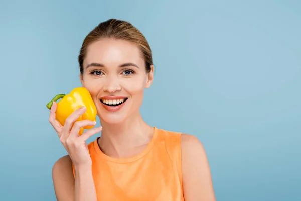 Charming woman with natural makeup holding bell pepper isolated on blue — Stock Photo