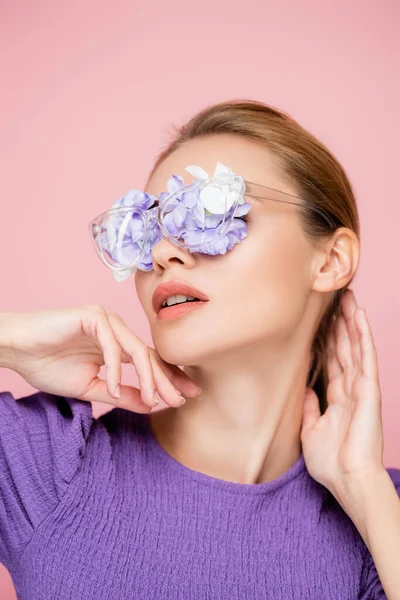 Femme sensuelle avec des fleurs dans les lunettes posant isolé sur rose — Photo de stock