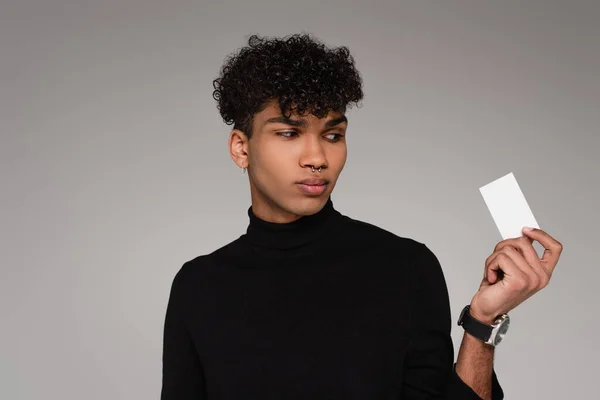 Young african american man in turtleneck sweater looking blank card isolated on grey — Stock Photo