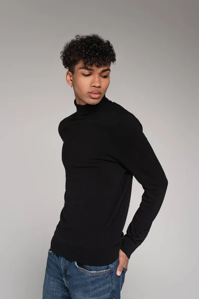 Young african american man with piercing looking away while posing isolated on grey — Stock Photo