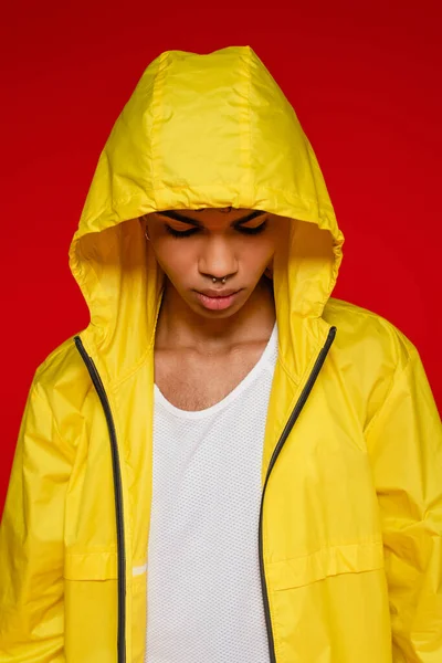 Стильний афроамериканський чоловік в жовтій куртці з капюшоном ізольований на червоному — стокове фото