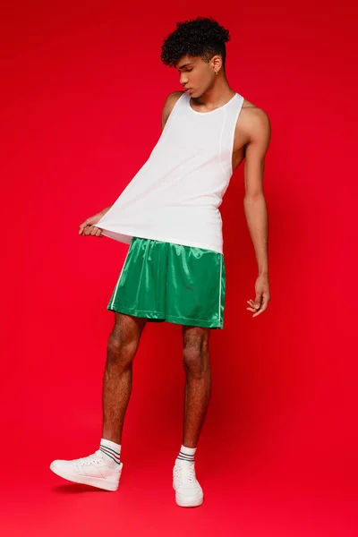 Pleine longueur de bouclé homme afro-américain réglage débardeur blanc sur rouge — Photo de stock