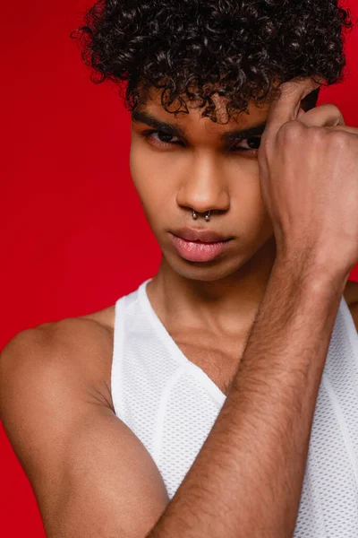 Muscular and pierced african american man in white tank top isolated on red — Stock Photo