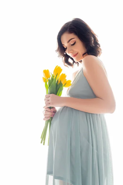 Jolie femme enceinte en robe tenant des tulipes isolées sur blanc — Photo de stock