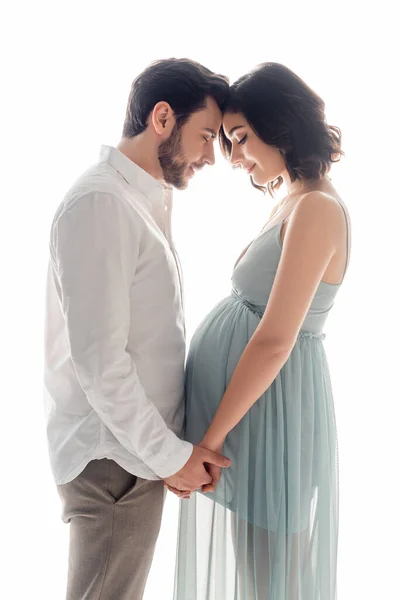 Vue latérale de la femme enceinte tenant les mains du mari isolé sur blanc — Photo de stock