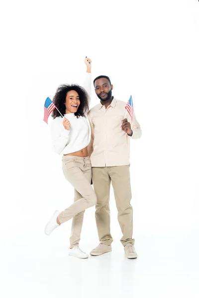 Excited african american woman showing win gesture while holding small flags of usa with husband on white — Stock Photo