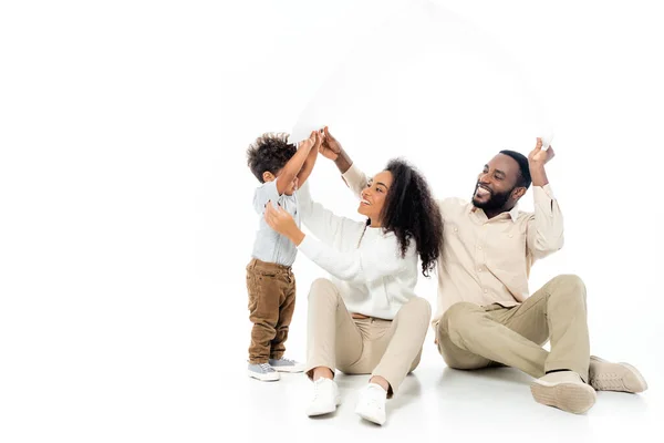 Heureux afro-américain famille tenant toit en papier sur blanc — Photo de stock