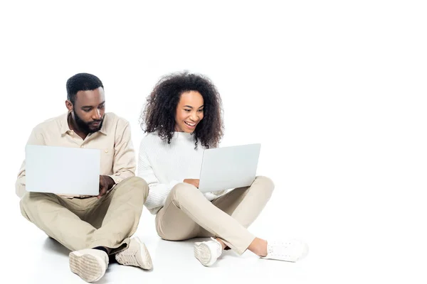 Curieux afro-américain homme regardant ordinateur portable dans les mains de femme joyeuse sur blanc — Photo de stock