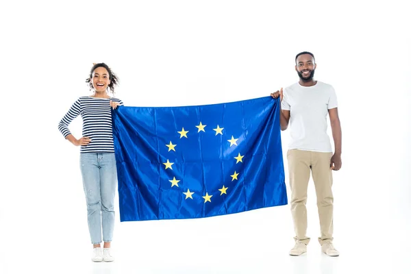 Молодая африканская американская пара улыбается в камеру, держа флаг Европейского союза на белом — стоковое фото