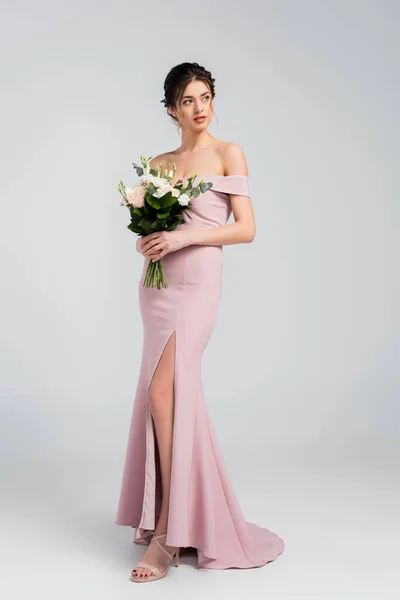 Full length view of sensual woman looking away while posing with wedding bouquet on grey — Stock Photo