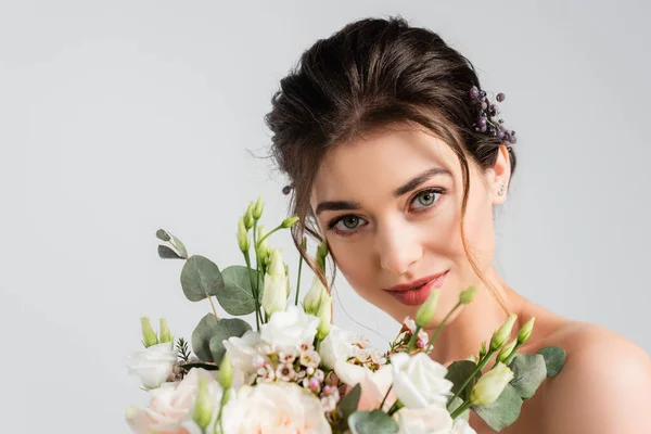 Charmante femme avec bouquet de mariage souriant à la caméra isolée sur gris — Photo de stock