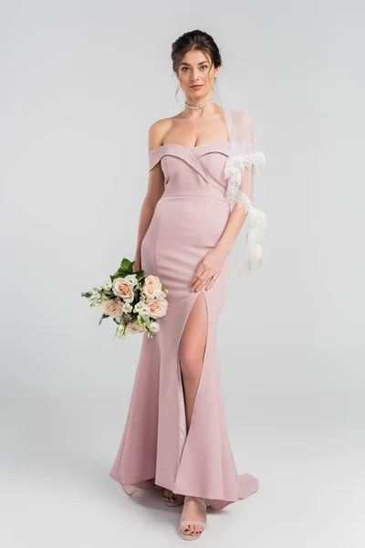 Full length view of elegant bride posing with wedding bouquet on grey — Stock Photo
