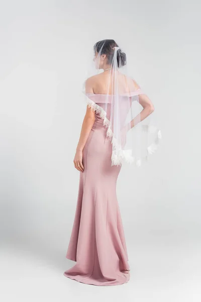 Full length view of bride in pink dress and veil posing on grey — Stock Photo