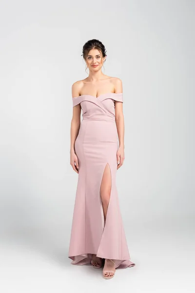 Full length view of woman in elegant wedding dress looking at camera on grey — Stock Photo
