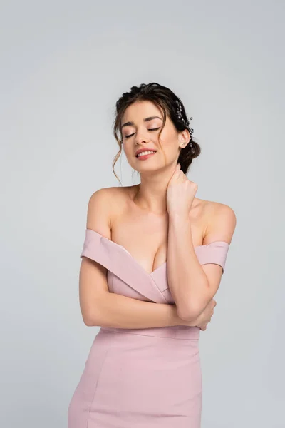 Smiling bride touching neck while posing with closed eyes isolated on grey — Stock Photo
