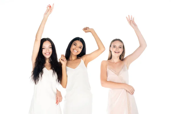 Excitadas mulheres inter-raciais em vestidos de pé com as mãos levantadas isolado no branco — Fotografia de Stock