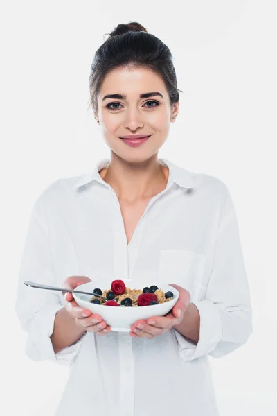 Smiling woman holding bowl of cereals and berries isolated on white — Stock Photo