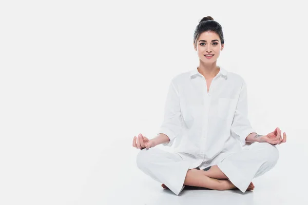 Mujer sonriente sentada en postura de yoga sobre fondo blanco - foto de stock