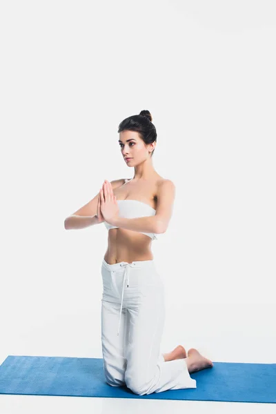 Bruna donna con mani che pregano praticando yoga sul tappeto fitness isolato su bianco — Foto stock