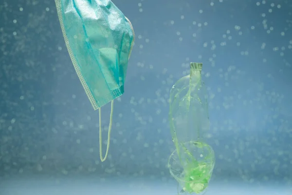 Basura de plástico cerca de máscara protectora usada en el agua, concepto de ecología - foto de stock
