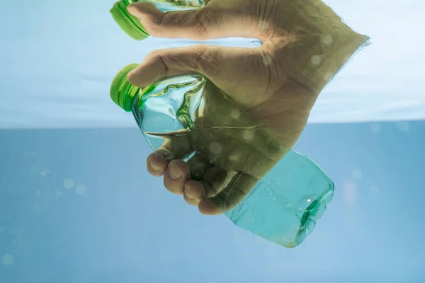 Vista ritagliata della mano maschile con bottiglia di plastica in acqua, concetto di ecologia — Foto stock