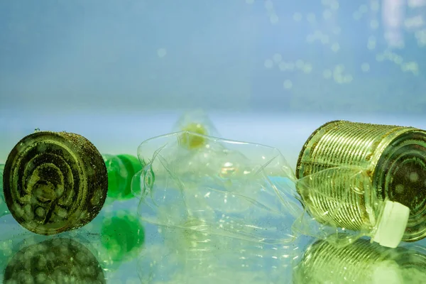 Botellas de plástico y latas oxidadas en agua, concepto de ecología - foto de stock