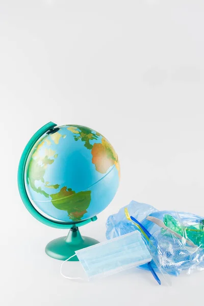 Globe near cellophane bag with plastic rubbish on grey, ecology concept — Stock Photo