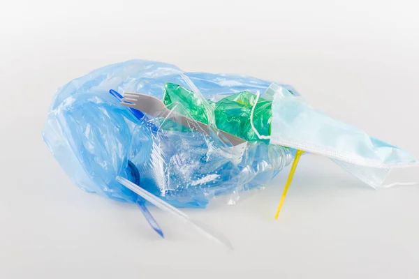 Maschera medica vicino spazzatura plastica sul grigio, concetto di ecologia — Foto stock