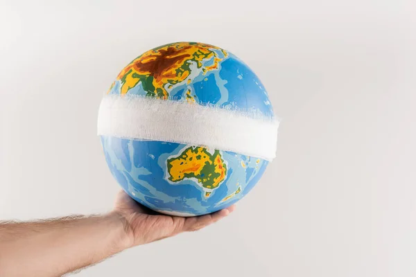 Partial view of man holding bandaged globe isolated on grey, ecology concept — Stock Photo